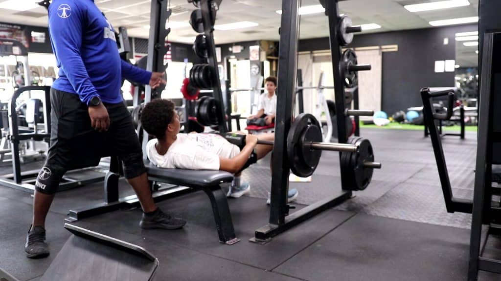 NASM-certified coach performing a safety movement screen for youth strength training at DaVinci Fitness in New Port Richey.